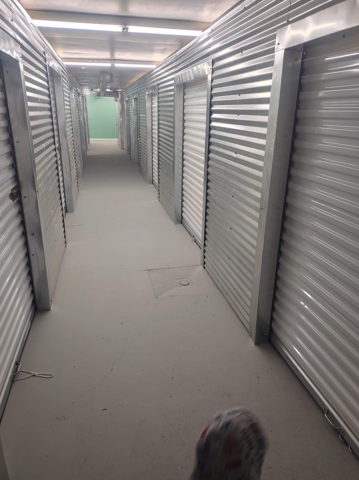 Interior corridor of climate-controlled self-storage facility with metal roll-up doors on both sides